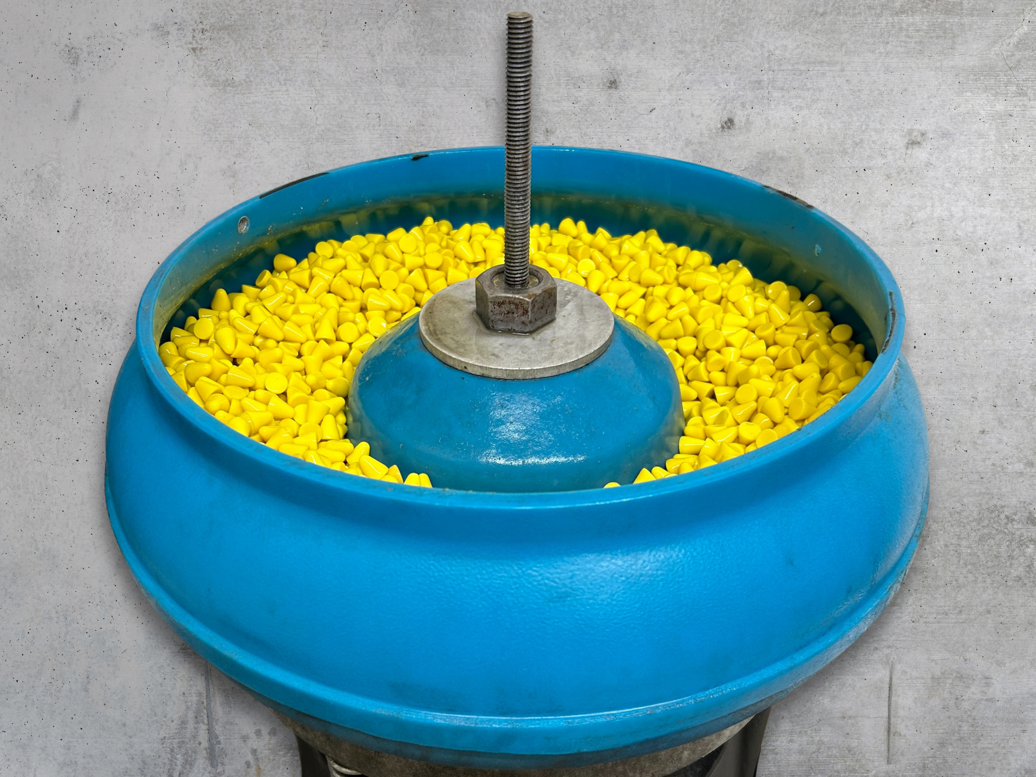 Top view of VA75 vibratory finishing machine filled with plastic PH1 10mm cone media against a grey background.