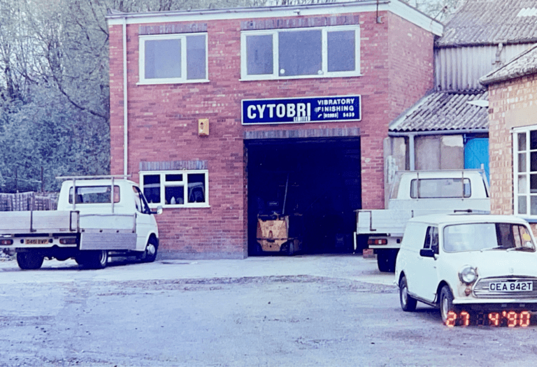 Historic View of CYTOBRI Subcontract Division Front view of CYTOBRI, Sharmic Engineering’s subcontract division, from many years ago, showing the building facade with old vehicles parked in the car park.