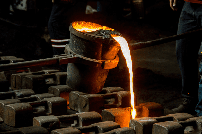 Molten metal being poured into moulds for casting in a foundry setting.