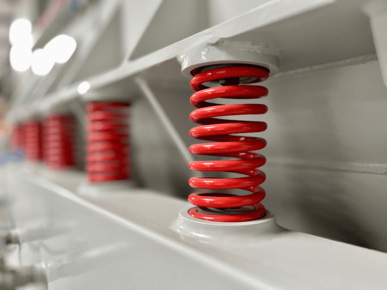 Close-up of springs supporting a vibratory trough/tub in a surface finishing machine.