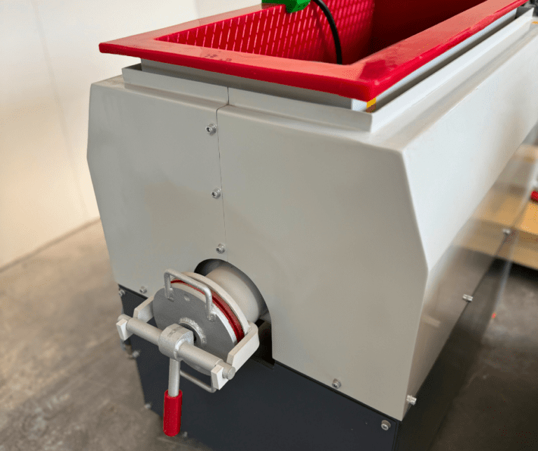 Side view of vibratory trough machine showing interior lining and discharge door close-up